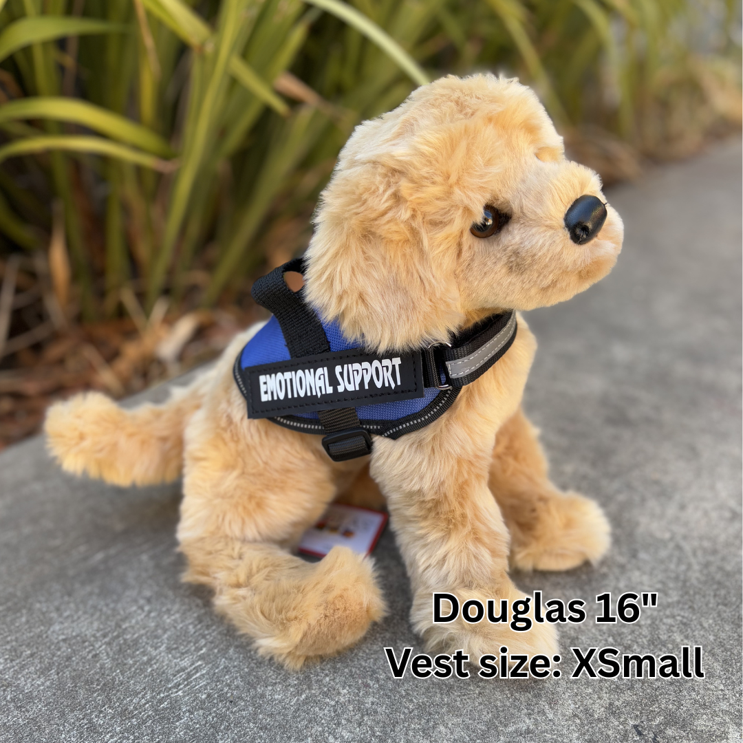 Plush toy dog with 'Emotional Support' vest on a concrete surface with plants in the background