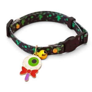 A black and green splatter-patterned pet collar with a small gold bell and a colorful eye-and-lollipop charm, shown on a white background.