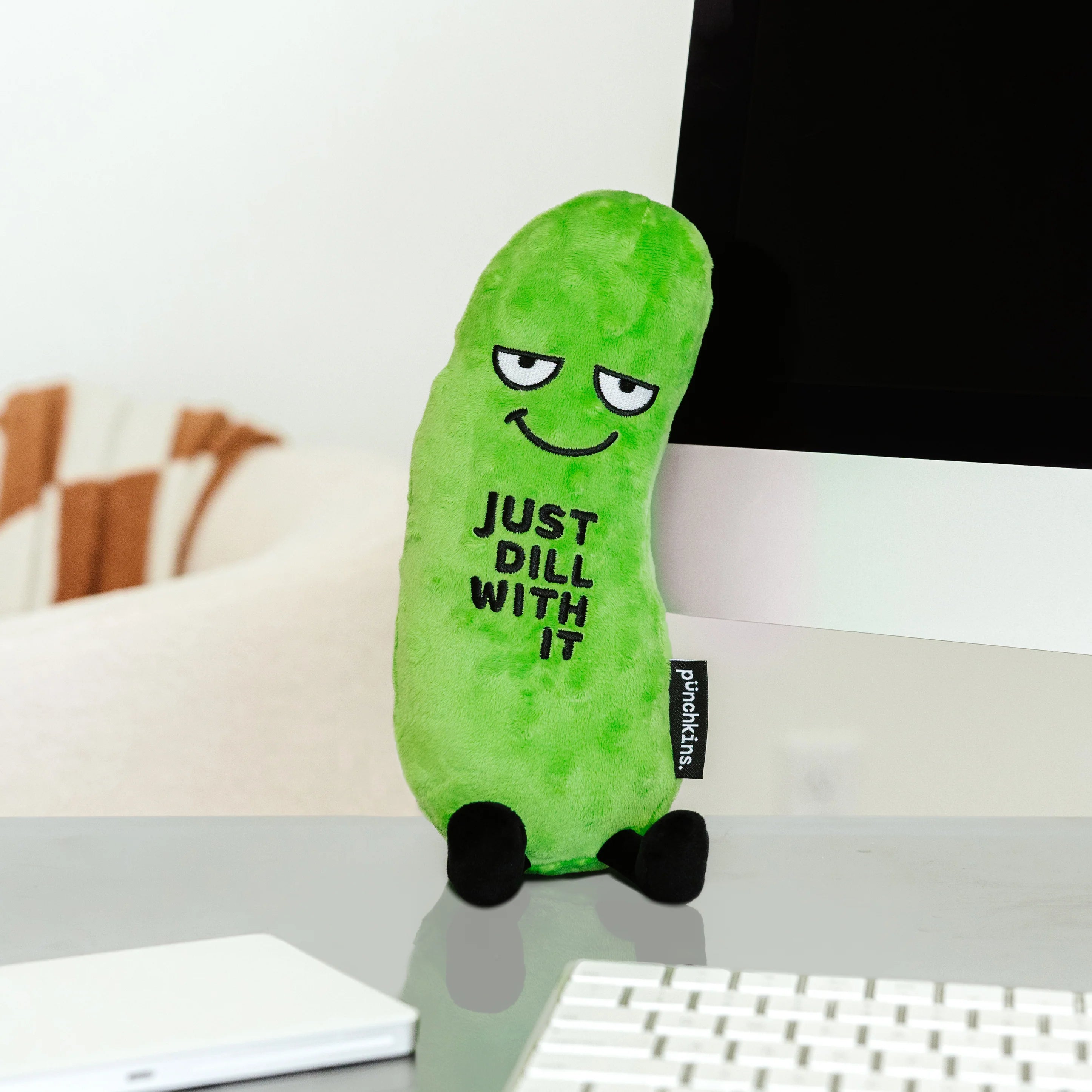 Green plush pickle with 'Just Dill With It' text on a desk