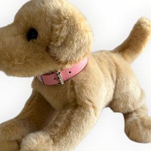 A plush golden retriever dog toy wearing a pink collar with a silver buckle, photographed against a plain white background.