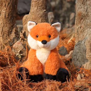 Plush fox toy in a natural setting with trees and foliage.