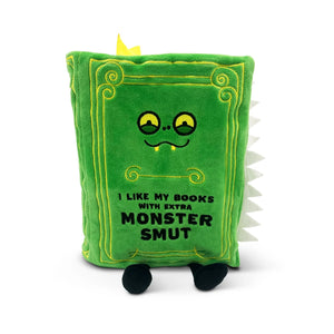 A green plush book toy with embroidered yellow details, cartoon eyes, and the text 'I LIKE MY BOOKS WITH EXTRA MONSTER SMUT' on the front, shown on a plain white background.