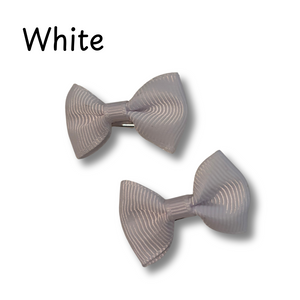 Two white hair bows with a ribbed texture on a white background.