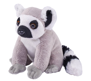 A plush toy lemur sitting on a plain white background. The toy has gray fur, a white chest and inner ears, black facial features and tail patches, and brown eyes.