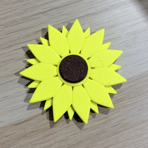 Flower-shaped object with bright yellow petals and a dark center on a wooden surface