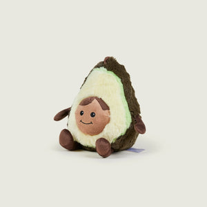 A plush avocado toy with a smiling face, sitting upright on a light beige background.