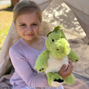 Girl hugging the green dinosaur plushie Warmies brand - weighted, lavender scented heat bag