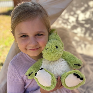 Girl hugging the green dinosaur plushie Warmies brand - weighted, lavender scented heat bag - sensory toy