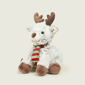 A white plush reindeer toy with brown antlers and hooves, wearing a red and green striped scarf, sitting against a light beige background.