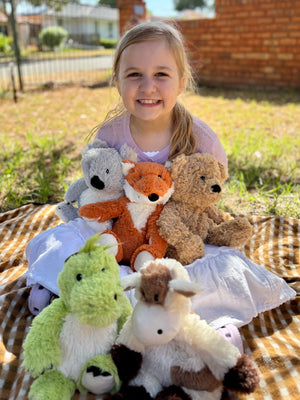 girl holding Warmies brand plushies - weighted, lavender scented heat bag