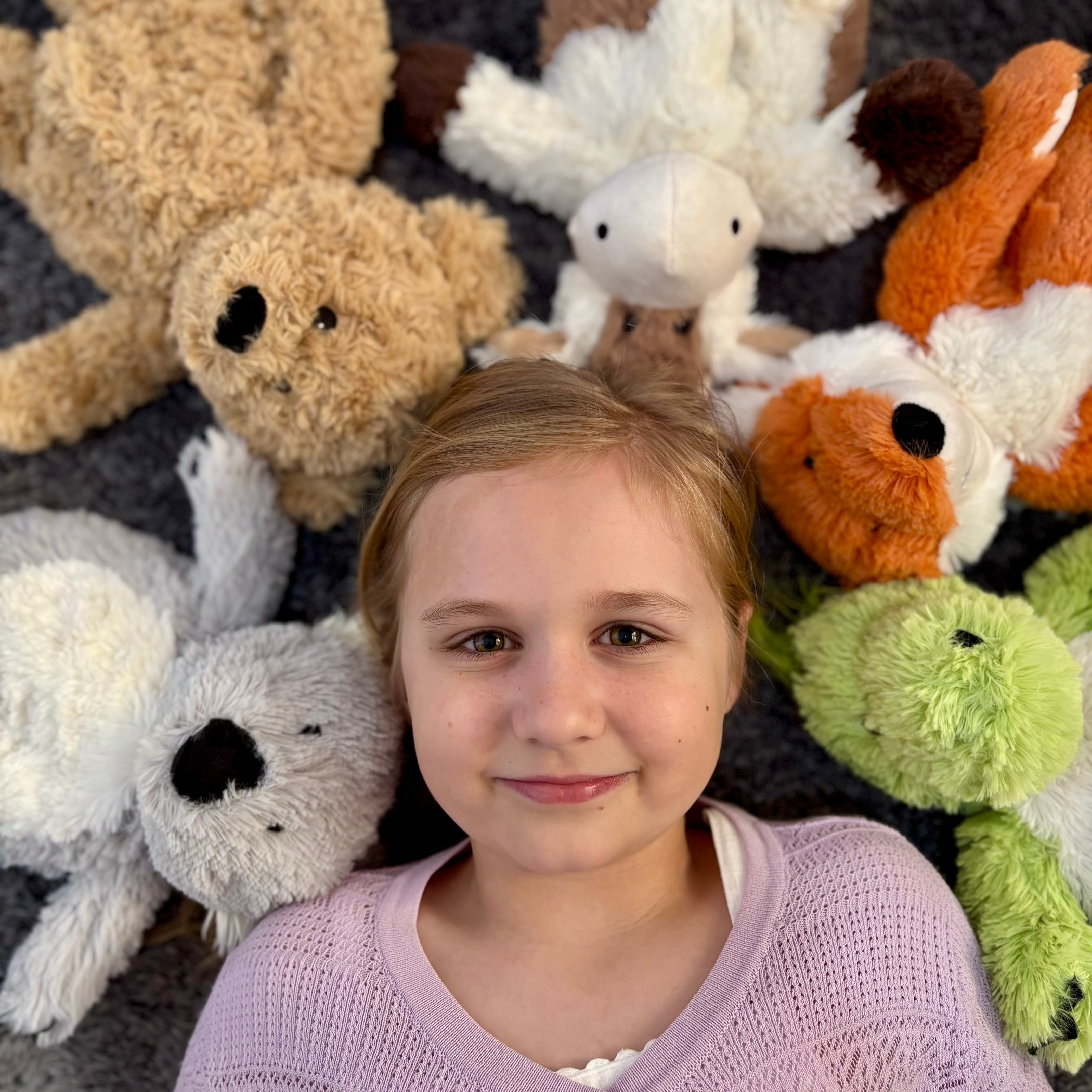 Girl lying down with warmies around her head - Warmies brand - weighted, lavender scented heat bag