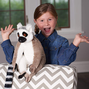 Child holding a plush lemur toy on a chevron-patterned ottoman.