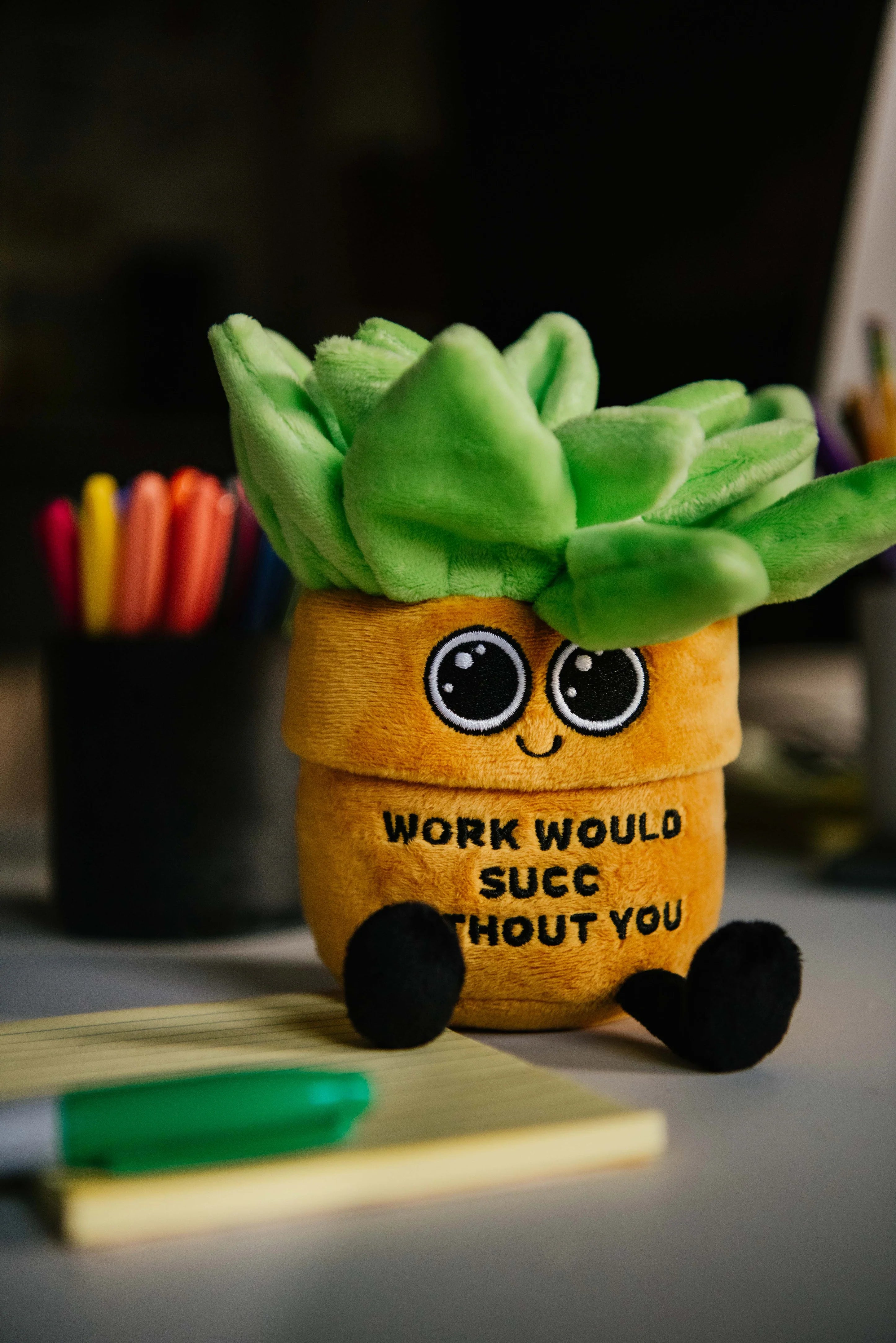 Plush succulent toy with a humorous message on a desk