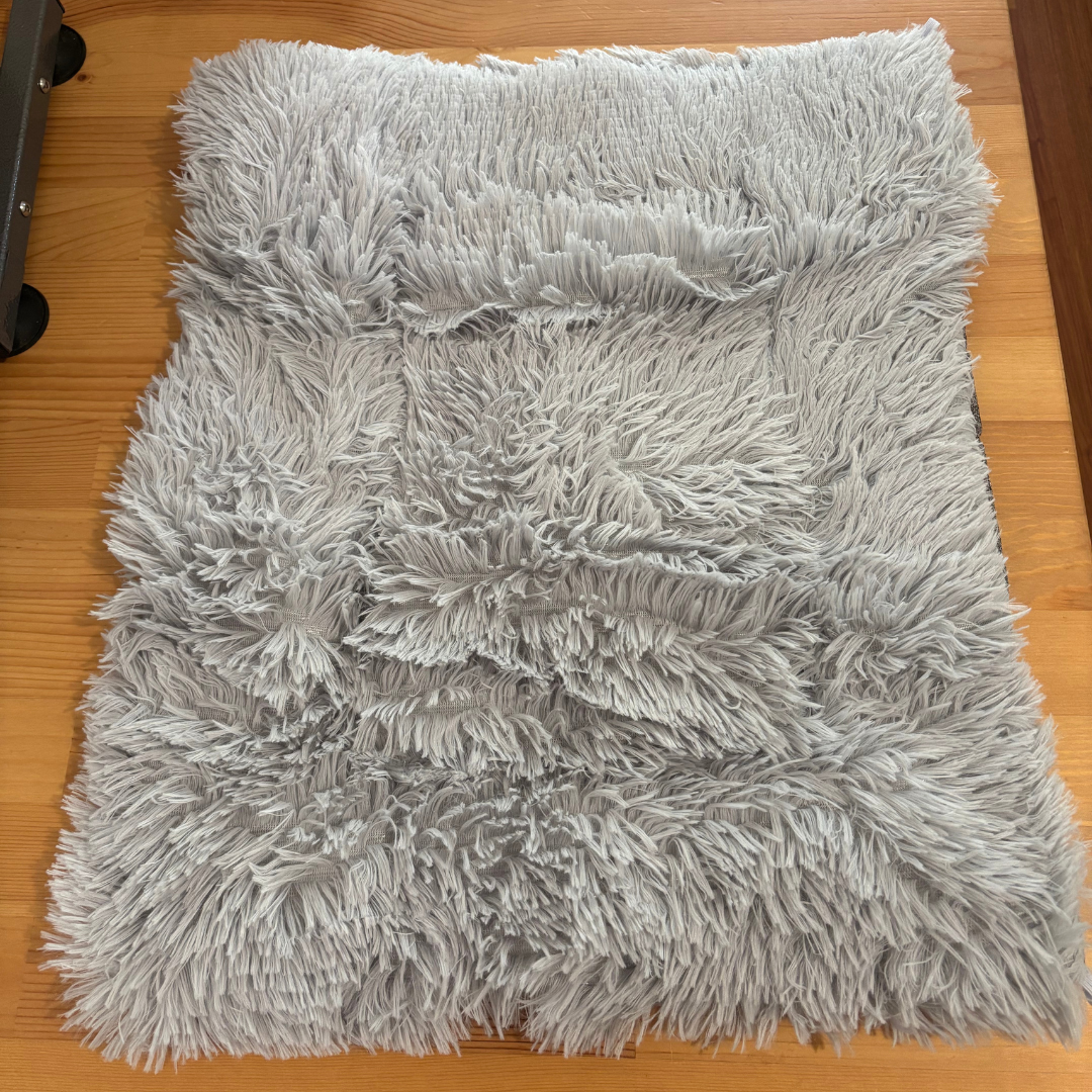 Gray fluffy pet bed on a wooden floor