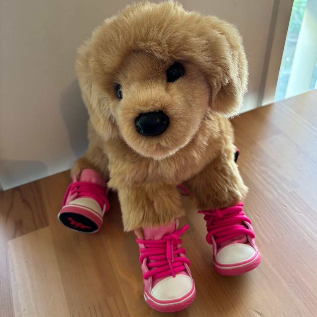 Plush dog toy with pink shoes on a wooden floor