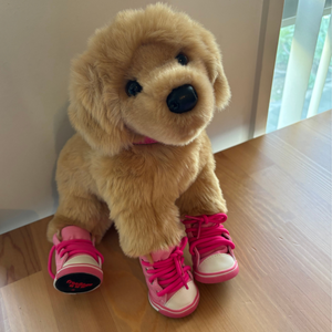 Plush dog toy with pink shoes on a wooden surface