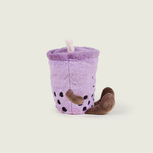 A plush toy designed to look like a purple boba tea cup with brown bean accents and a small white straw, photographed on a plain light beige background.