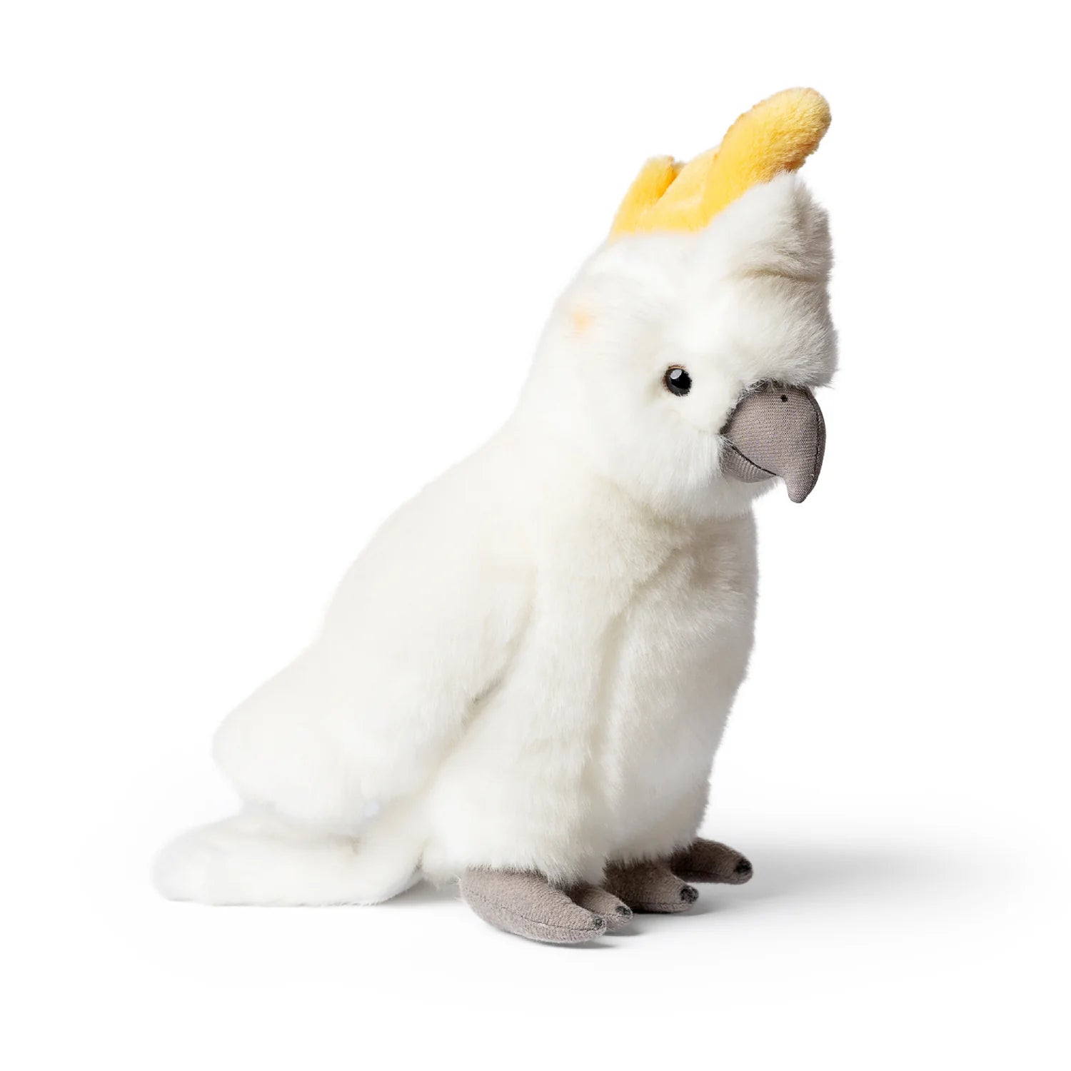 A plush cockatoo toy sitting upright on a clean white background. The toy is primarily white with a bright yellow crest on its head, a gray beak, and gray feet.