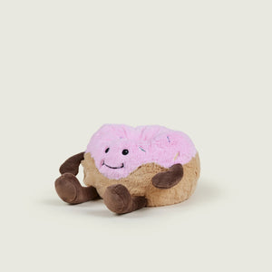 Plush toy resembling a donut with pink icing on a beige background