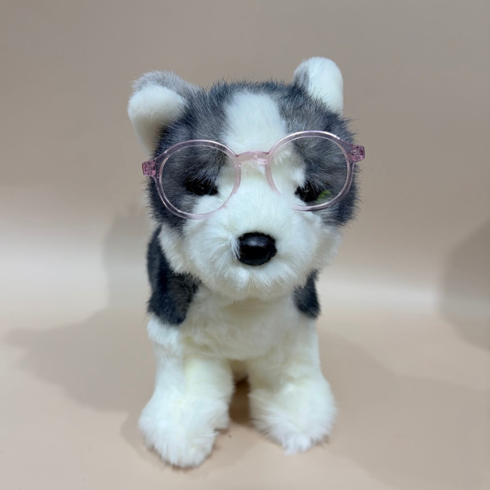 Plush toy husky dog wearing pink glasses on a beige background