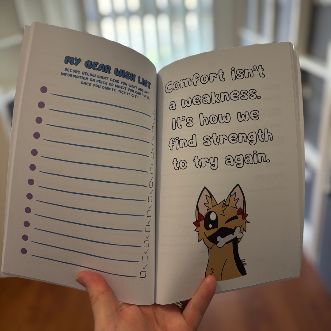 Open notebook with motivational quote and cartoon character, held by a hand.