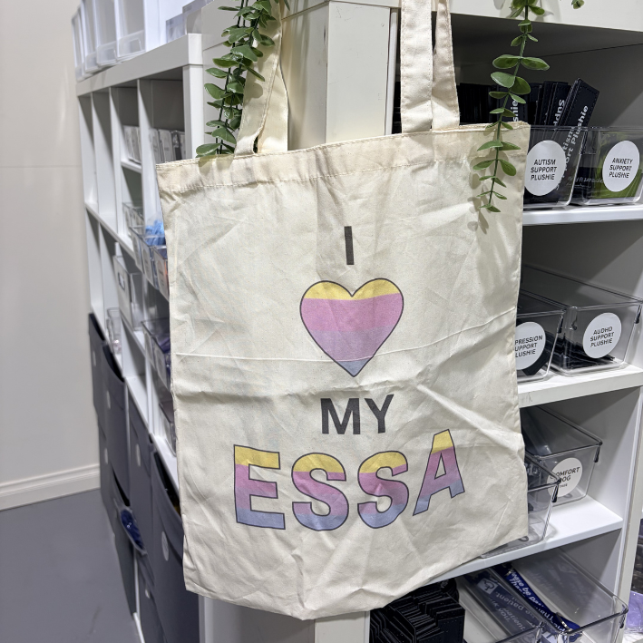 Tote bag with 'I ❤️ MY ESSA' text hanging on a shelf.
