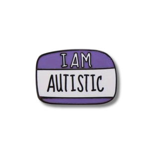 Enamel pin with 'I AM AUTISTIC' text on a white background