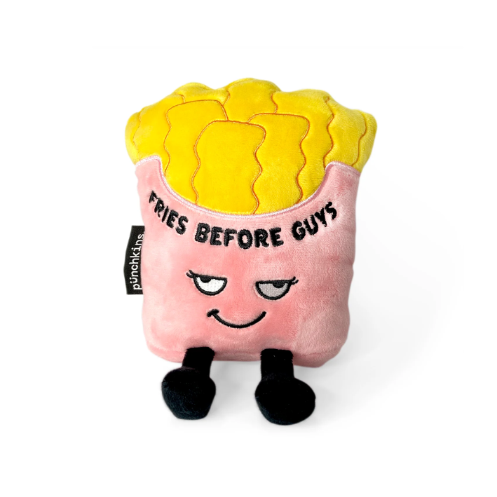 A plush toy shaped like a french fries container, with yellow textured top resembling fried fries, a pink body, embroidered face, and black feet. The front reads 'FRIES BEFORE GUYS' and has a visible 'puncktins' tag on the side.