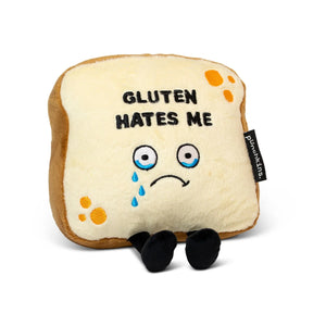A plush cushion shaped like a slice of sad bread with embroidered eyes, tears, and the text 'GLUTEN HATES ME' on a white background.