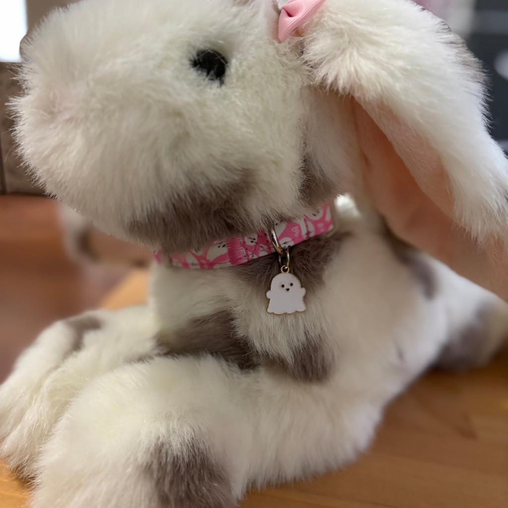 Plush toy with a pink collar and tag on a wooden floor