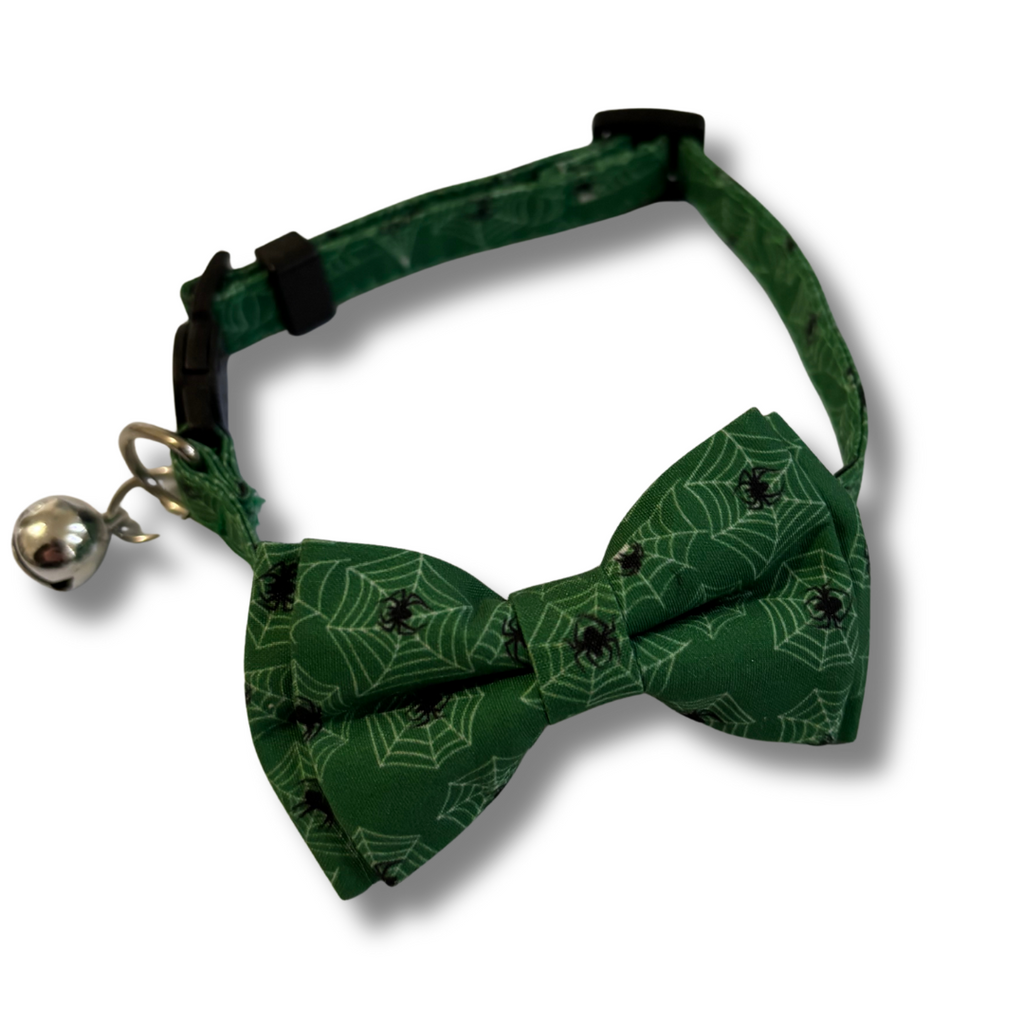 Green bow tie with spider web pattern and bell on a white background