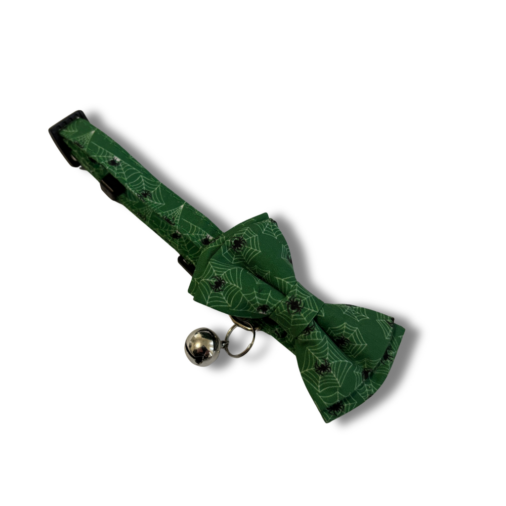 Green bow tie with black patterns and a bell on a white background