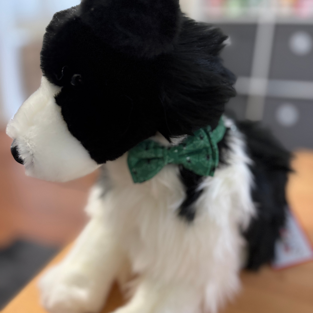 Plush toy dog with a green bow tie on a blurred background