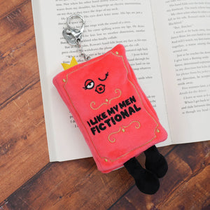 Red plush keychain with 'I Like My Men Fictional' text on an open book.