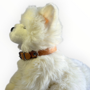 A white fluffy plush dog wearing a tan leather collar with silver hardware, shown in profile against a plain white background.