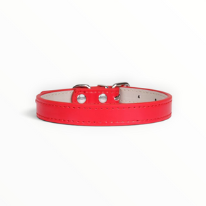 A red faux leather collar with silver metal hardware and a light beige interior, shown on a plain white background.