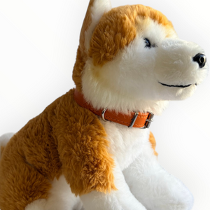 A plush dog toy with fluffy orange and white fur, wearing an orange collar, photographed against a plain white background.