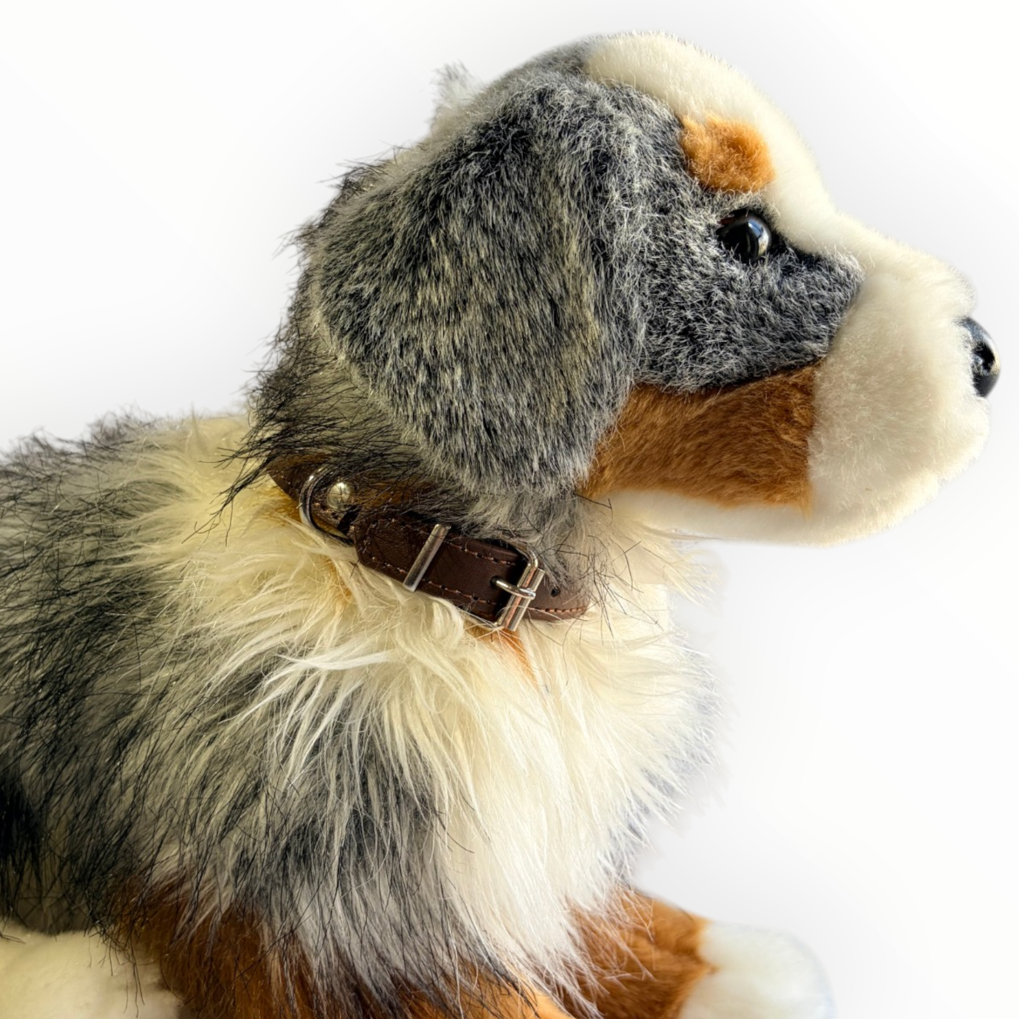A close-up side profile of a plush dog toy wearing a brown collar, photographed against a clean white background.