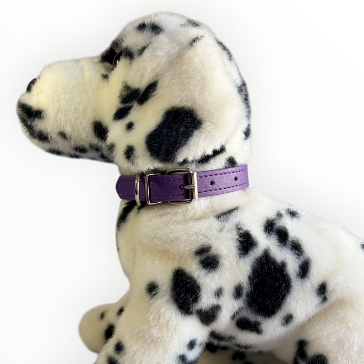 A plush Dalmatian dog toy wearing a purple collar with a silver buckle, photographed against a plain white background.