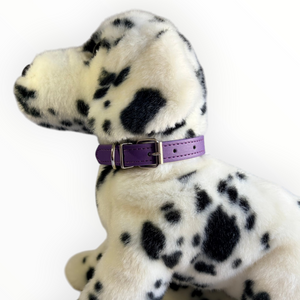 A plush Dalmatian dog toy wearing a purple collar with a silver buckle, photographed against a plain white background.
