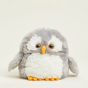 A plush toy penguin with gray and white fur, large brown eyes, and orange beak and feet, photographed against a plain light beige background.