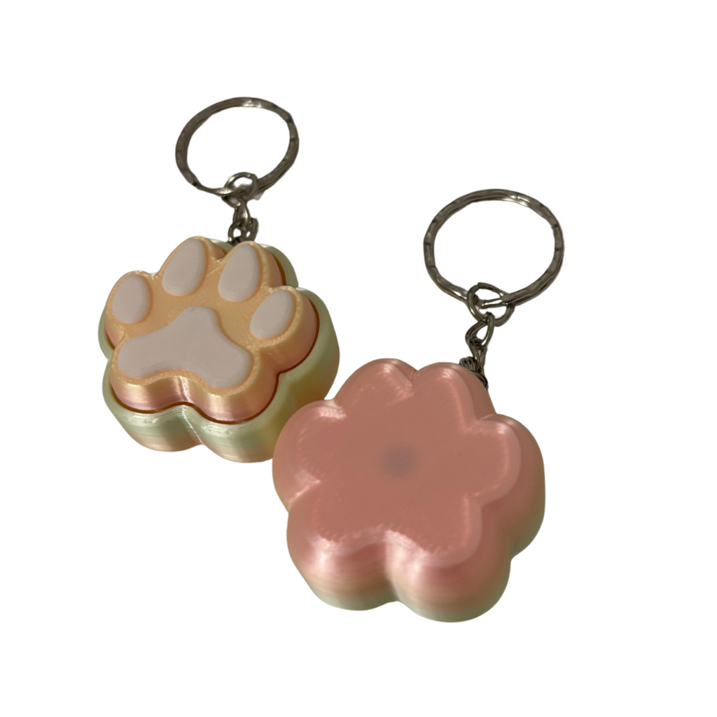 Two keychains shaped like a paw print and a flower on a white background