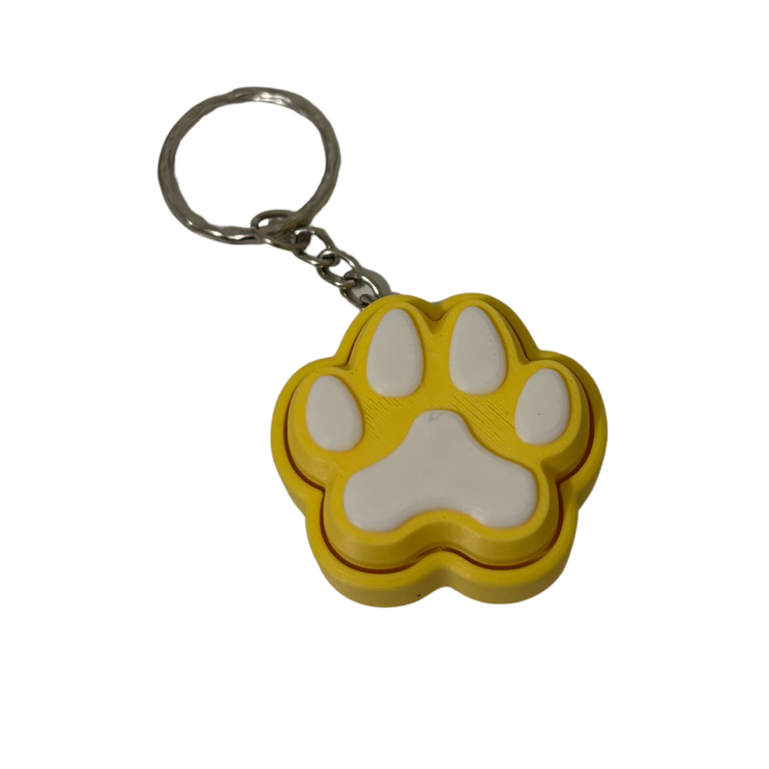 Yellow keychain with a white paw print on a white background