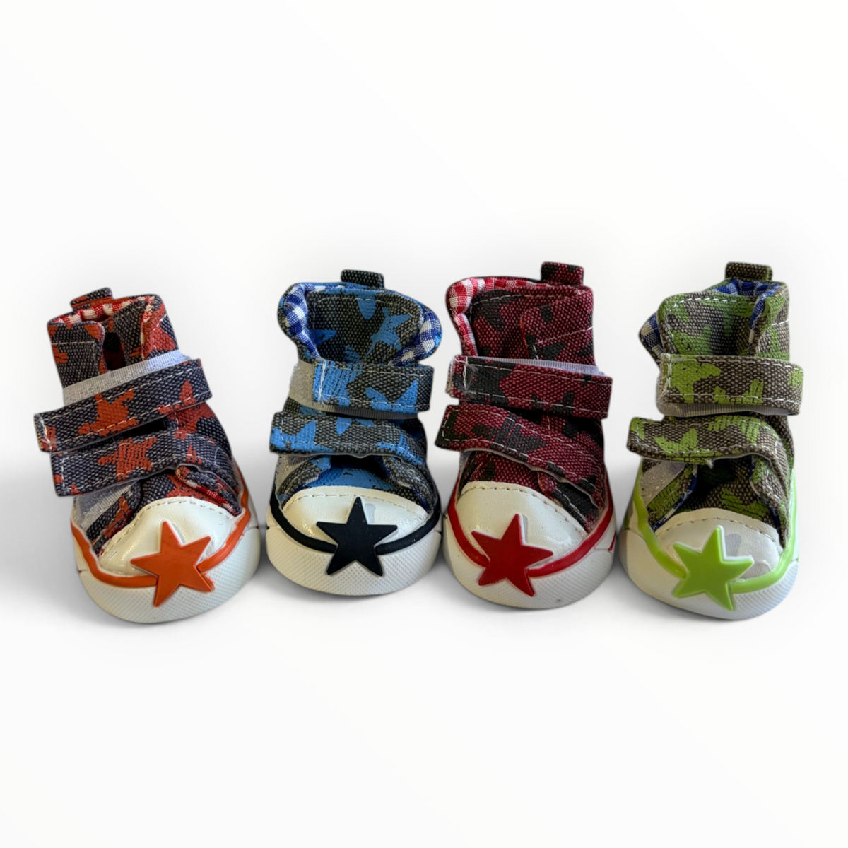 Four miniature high-top baby shoes lined up on a white background, each featuring a different camouflage pattern and a contrasting star on the toe cap.