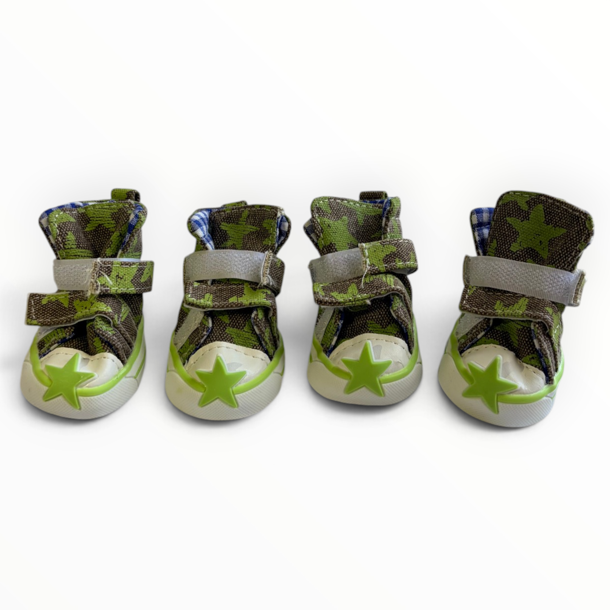 Four green camouflage high-top baby shoes with gray velcro straps and lime green star details on the toes, arranged in a row against a white background.