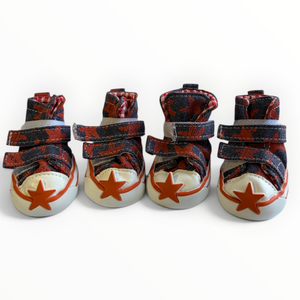 Four miniature high-top dog shoes styled like classic high-top sneakers, featuring red and black patterned fabric straps, white toe caps, and red star details on a white background.