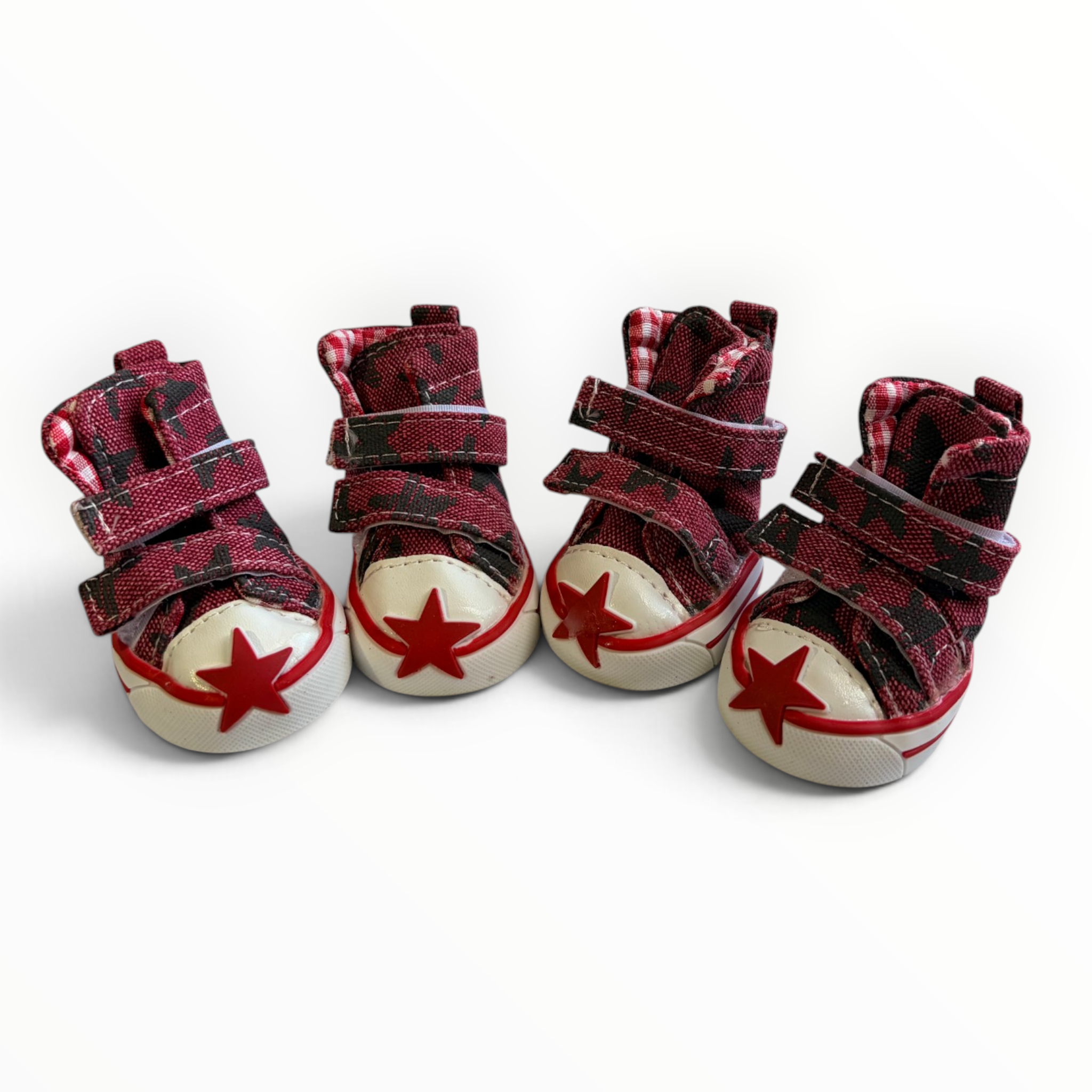 Four miniature high-top baby shoes in a red and black plaid pattern, featuring cream-colored toe caps with red star details and double hook-and-loop straps.
