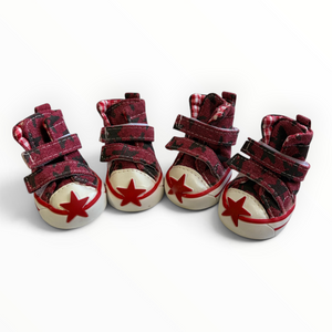 Four miniature high-top baby shoes in a red and black plaid pattern, featuring cream-colored toe caps with red star details and double hook-and-loop straps.