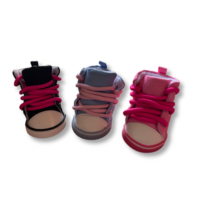 Three pairs of children's shoes with pink laces on a white background