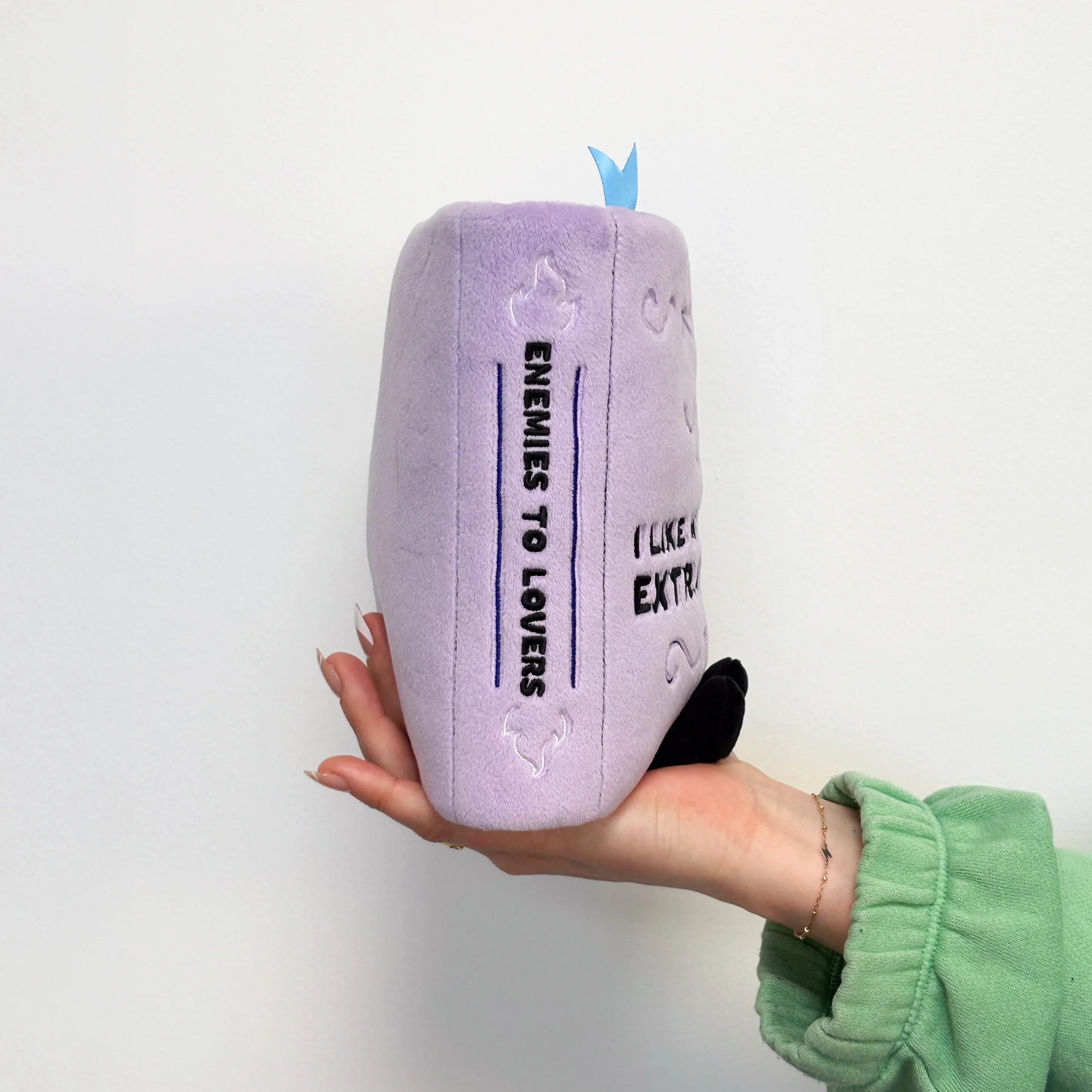 Purple plush pillow with text held by a person against a white background